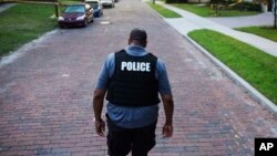 A police officer walks toward a crime scene in Florida. Four police officers were shot in two separate shootings in two Florida cities, Aug. 19, 2017.