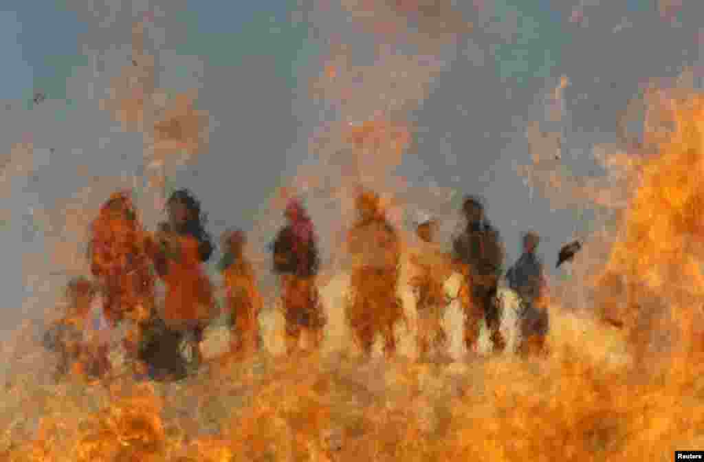 Afghan children watch burning expired medical items and food on the outskirts of Jalalabad. 