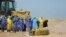 Iraqi health ministry workers pray by a coffin of a person who died from coronavirus at a new cemetery for the people who died from Covid-19 outside the town of Najaf, Iraq, March 30, 2020.