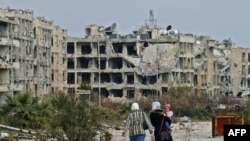 FILE - Residents of a suburban neighborhood on the edge of the northern Syrian city of Aleppo return to their homes to check the damage caused by fighting between regime forces and rebel fighters, February 18, 2020..