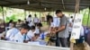 Officials check documents of a voter as he arrives to cast his ballot at a polling station during Sri Lanka's presidential election in Colombo on Sept. 21, 2024.