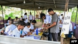 Officials check documents of a voter as he arrives to cast his ballot at a polling station during Sri Lanka's presidential election in Colombo on Sept. 21, 2024.