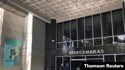 Personas frente al edificio de la cámara empresarial venezolana durante la inauguración de la asamblea anual de Fedecamaras, en Caracas. 