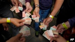 Turistas muestran los billetes viejos de bolívares para usarlos como tiques para intercambiarlos por comida en un tour realizado en Caracas, Venezuela, el 21 de agosto de 2021. La inflación entre enero y junio fue de 100 puntos, según una organización no gubernamental.