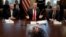 Predsjednik Trump na sastanku kabineta u Bijeloj kući, dok se na stolu ispred nalazi poster s njegovim likom (Foto: AP/Evan Vucci)
