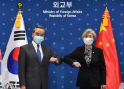 FILE - Chinese Foreign Minister Wang Yi (L) and South Korean Foreign Minister Kang Kyung-wha (R) greet prior to their meeting at the Foreign Ministry in Seoul, South Korea, Nov. 26, 2020.