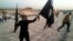 FILE - An Islamic State fighter holds the extremist group's signature flag and a weapon in the Iraqi city Mosul, June 23, 2014. Preparations are underway to wrest the city from IS control.