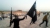 FILE - A fighter of the Islamic State of Iraq and the Levant (ISIL) holds an ISIL flag and a weapon on a street in the city of Mosul, June 23, 2014.