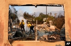 Firefighters extinguish burning embers at a house on Santa Rosa Avenue, also known as Christmas Tree Lane, Jan. 9, 2025, in Altadena, Calif.