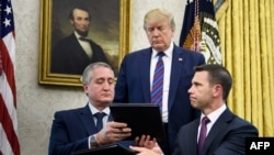 President Donald Trump watches as Guatemalan Interior Minister Enrique Degenhart, left, and acting U.S.Secretary of Homeland Security Kevin McAleenan exchange documents while signing a safe-third-country migration agreement in Washington, July 26, 2019.