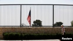 FILE - A woman walks with a dog past the U.S. consulate in Jerusalem, Aug. 4, 2013.