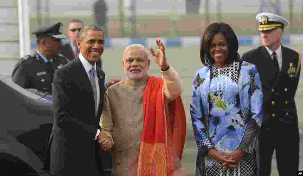 President Barack Obama, left, shakes hand with Indian Prime Minister Narendra Modi, center, as first lady Michelle Obama stands beside them, upon arrival at the Palam Air Force Station in New Delhi, Jan. 25, 2015.