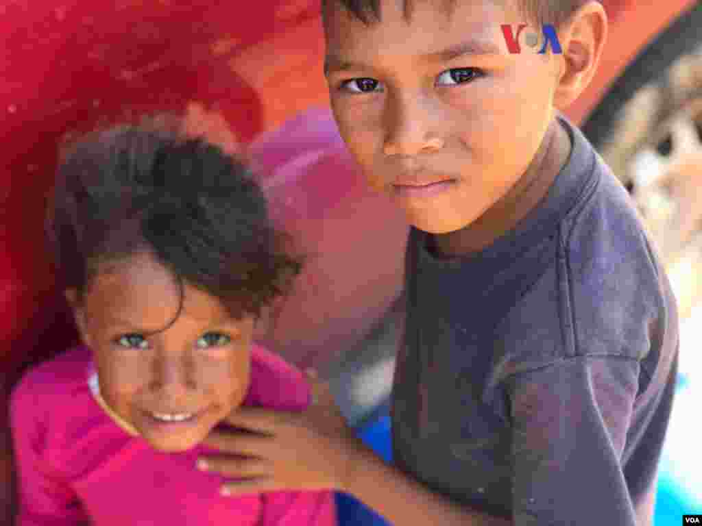 Dos niños miran a la cámara en el refugio improvisado&nbsp;creado por venezolanos en el vecindario Jardim Floresta, fronterizo de Brasil. Foto: Celia Mendoza - VOA