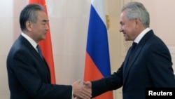 Sekretaris Dewan Keamanan Rusia Sergei Shoigu berjabat tangan dengan Menteri Luar Negeri China Wang Yi saat Pertemuan Pejabat Tinggi Keamanan BRICS di Saint Petersburg, Rusia, 10 September 2024. (Foto: via Reuters)