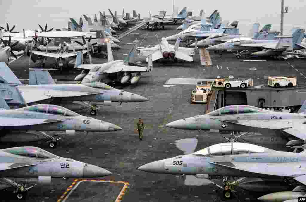 A U.S. Navy officer walks past fighter jets parked on the flight deck of the Nimitz-class aircraft carrier USS Abraham during a media tour in Port Klang, on the outskirts of Kuala Lumpur, Malaysia.