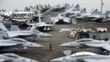 A U.S. Navy officer walks past fighter jets parked on the flight deck of the Nimitz-class aircraft carrier USS Abraham during a media tour in Port Klang, on the outskirts of Kuala Lumpur, Malaysia, Nov. 26, 2024.