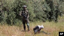 An Israeli soldier stands over handcuffed and blindfolded Osama Hajahjeh, 16, after he was shot near the village of Tekoa, West Bank, Apri 18, 2019. 