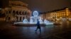 A man passes by the illuminated fountain in front of the Old Opera in Frankfurt, Germany, Dec. 10, 2020.