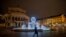 A man passes by the illuminated fountain in front of the Old Opera in Frankfurt, Germany, Dec. 10, 2020.
