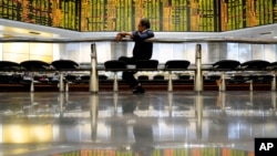 A visitor sits in front of stock trading boards at a private stock market gallery in Kuala Lumpur, Malaysia, Dec. 13, 2018. Shares rose in Asia on Thursday after a strong overnight finish on Wall Street. 