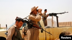 FILE - Members of Kurdish security forces patrol after clashes with Islamic State militants in the village of Bashir, south of the city of Kirkuk, Iraq, June 29, 2014.