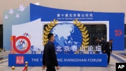 FILE - Workers walk past the entrance to the venue hosting the Xiangshan Forum in Beijing, China, Oct. 29, 2023.