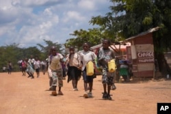 Children walk and play music on plastic jugs at the Epulu village in the Okapi Wildlife Reserve in Congo, Sept. 21, 2024. (AP Photo/Sam Mednick)