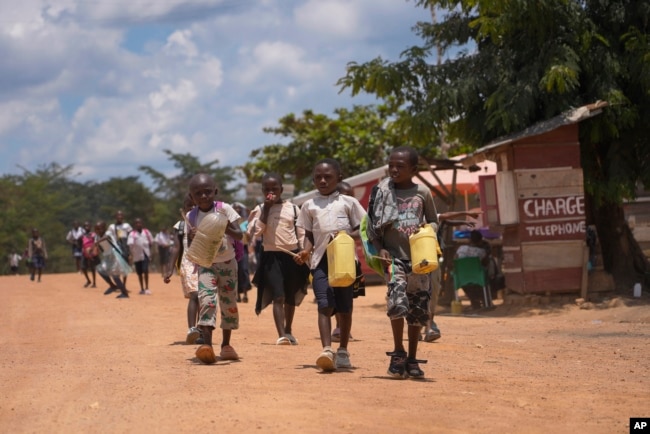 Children walk and play music on plastic jugs at the Epulu village in the Okapi Wildlife Reserve in Congo, Sept. 21, 2024. (AP Photo/Sam Mednick)