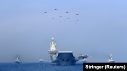 中国海军辽宁号航母与军舰和战机在进行军事表演。（2018年4月12日）