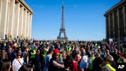 French "yellow vest" protesters, with the Eiffel Tower in the background, rally in support of an older female activist injured in a recent confrontation with police, March 30, 2019, in Trocadero Square, in Paris.