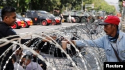 A policeman buys a drink as he stands guard in front of U.S. embassy in Jakarta, Indonesia, May 11, 2018. 