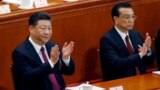 Chinese President Xi Jinping, left, and Chinese Premier Li Keqiang applaud during the opening session of the annual National People's Congress at the Great Hall of the People in Beijing, March 5, 2018.