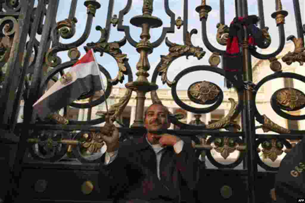 An anti-government protester gestures as he sits outside the Egyptian Parliament in Cairo, Egypt, Wednesday, Feb. 9, 2011. Around 2,000 protesters waved huge flags outside the parliament, several blocks from Tahrir Square, where they moved a day earlier i