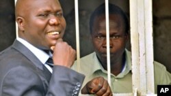 Thomas Kwoyelo (R), a former director of field operations in the rebel group Lord's Resistance Army, talks to his lawyer, Caleb Alaka, after the court ordered he should be released, in Kampala, Uganda, November 2011. (file photo)