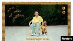 Raja Thailand Bhumibol Adulyadej berpose dengan anjing favoritnya, Khun Thongdaeng, pada sebuah kartu ucapan selamat tahun baru yang ditujukan kepada rakyat Thailand, 7 Desember 2005.