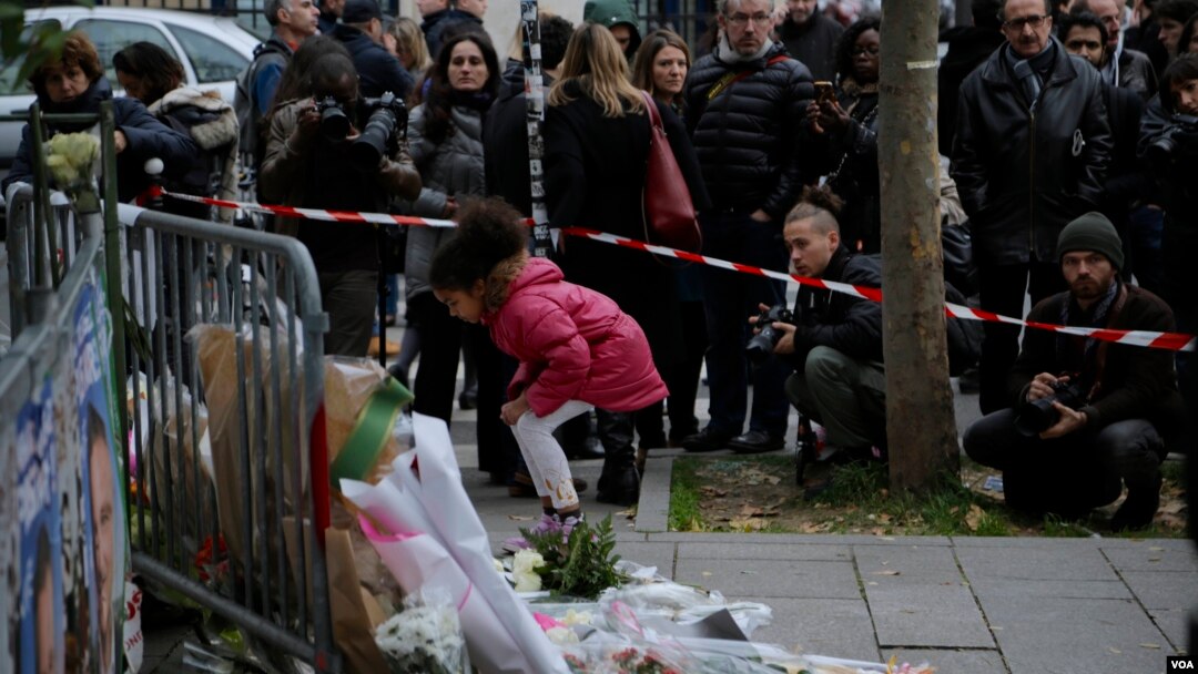 A girl lays flowers as part of a memorial to victims of the terror attacks in Paris, France, Nov. 14, 2015.