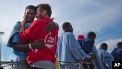 Kybumba Fran, 25, dari Kamerun, bersama kepala misi LSM Proactive Open Arms Riccardo Gatti dari Italia, saat dia meninggalkan kapal penyelamat Golfo Azzurro, setibanya di pelabuhan Pozzallo di selatan Sisilia, Italia. Kybumba bersama 220 migran diselamatkan kapal itu di Laut Tengah, 5 Februari 2017.