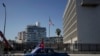 Sebuah mobil klasik yang membawa bendera Kuba tampak melewati kantor Kedutaan Besar AS di Havana, Kuba, pada 28 Maret 2021. (Foto: Reuters/Alexandre Meneghini)