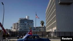 Sebuah mobil klasik yang membawa bendera Kuba tampak melewati kantor Kedutaan Besar AS di Havana, Kuba, pada 28 Maret 2021. (Foto: Reuters/Alexandre Meneghini)