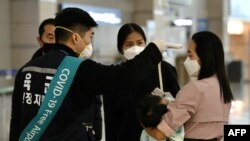 17일 한국 인천국제공항에서 육군 지원팀 소속 군인이 여행객의 체온을 측정하고 있다.