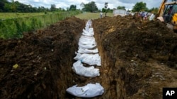 Un equipo forense entierra a un grupo de migrantes que murieron tratando de cruzar la brecha del Darién, en una fosa común en el cementerio de Guayabillo en Agua Fría, Panamá, el jueves 30 de septiembre de 2021. 