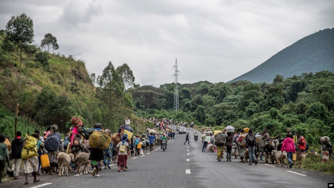 FILE: People walk on the road near Kibumba, north of Goma, Democratic Republic of Congo, as they flee fighting between DRC forces and M23 rebels in North Kivu, on Tues. May 24, 2022.