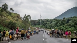 FILE: People walk on the road near Kibumba, north of Goma, Democratic Republic of Congo, as they flee fighting between DRC forces and M23 rebels in North Kivu, on Tues. May 24, 2022.