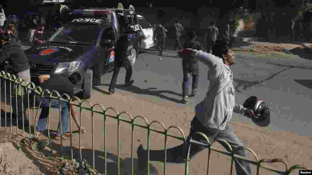 Les partisans du Jamiat Talaba l&#39;Islam (ITC), l&#39;aile étudiante du Jamaat Islami (JI), jettent des pierres sur des policiers lors d&#39;une manifestation contre l&#39;hebdomadaire satirique français Charlie Hebdo, Karachi, au Pakistan, le 16 janvier 2015.