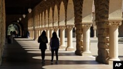 FILE- In this March 14, 2019, file photo students walk on the Stanford University campus in Santa Clara, Calif.