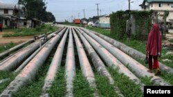 FILE - A girl walks on a gas pipeline running through Okrika community near Nigeria's oil hub city of Port Harcourt.