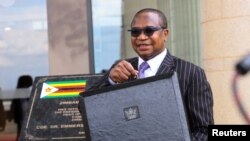 Zimbabwe's Finance Minister Mthuli Ncube stands with a briefcase at the Parliament Building in Mt Hampden on the day he presents the 2024 National Budget, Harare, Nov. 30, 2023.