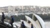 Orang-orang mendaki Sydney Harbour Bridge di atas Sydney Opera House bersama pemandu wisata di Sydney, Australia, 22 Juni 2021. (REUTERS/Loren Elliott)