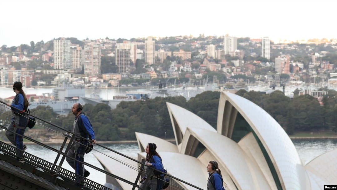 Orang-orang mendaki Sydney Harbour Bridge di atas Sydney Opera House bersama pemandu wisata di Sydney, Australia, 22 Juni 2021. (REUTERS/Loren Elliott)