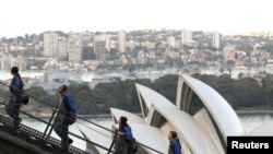 Orang-orang mendaki Sydney Harbour Bridge di atas Sydney Opera House bersama pemandu wisata di Sydney, Australia, 22 Juni 2021. (REUTERS/Loren Elliott)